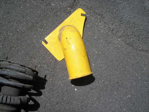 1991 Ford Taurus - A yellow plastic component and a car's suspension system are shown on a paved surface.