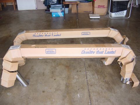 1990 Ford Bronco - Two boxed car parts are shown on a concrete floor, with text indicating they are made of genuine steel.