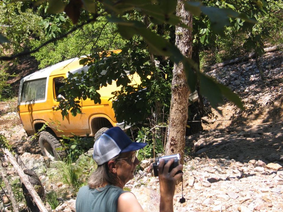 Yellow SUV with white roof on rocky terrain, viewed from the side