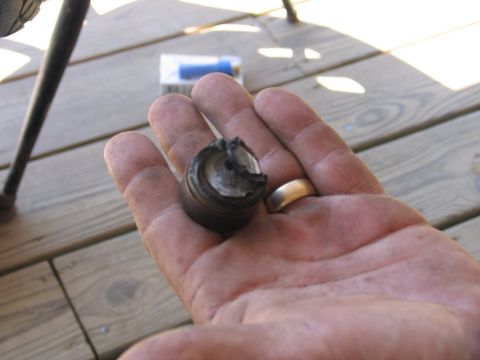 1995 Ford Bronco - A damaged metal part is held in a hand, resting on a wooden deck.