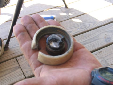 1995 Ford Bronco - A hand displays a worn bearing race and roller bearing, possibly from a vehicle repair.