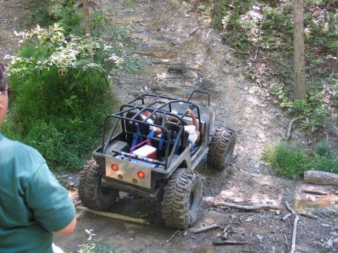 1995 Ford Bronco - Off-road Jeep navigates a challenging dirt and rock incline during an outdoor event.