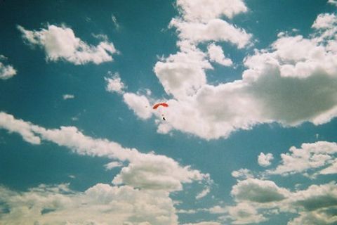 1972 Ford Ranchero - A lone skydiver navigates the sky under a bright red parachute, surrounded by fluffy white clouds.