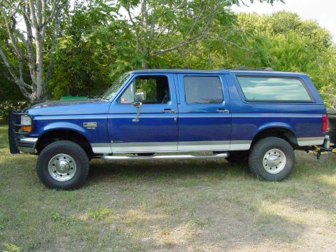 1994 Ford C-350 (Centurion Conversions) - Side view of a blue extended cab pickup truck with a camper shell, possibly a Ford F-250 from the early 1990s.