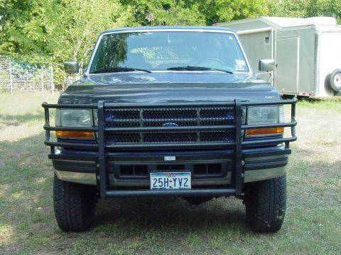 1994 Ford C-350 (Centurion Conversions) - This Ford F-Series truck, likely from the mid-1990s, is equipped with a heavy-duty brush guard and parked outdoors.