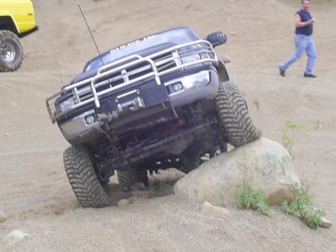 1977 Ford F-150 - A dark pickup truck navigates an obstacle course, with another vehicle visible in the distance.