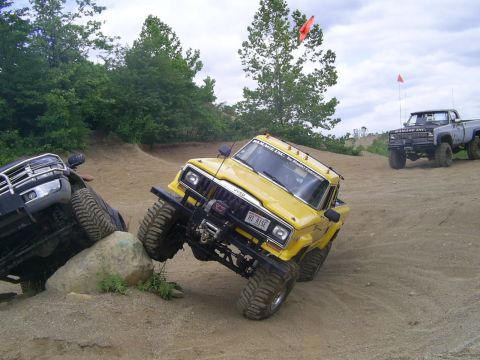 1977 Ford F-150 - Off-road vehicles navigate a challenging rocky terrain on a sunny day.