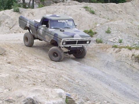 1977 Ford F-150 - This lifted 1977 Ford F-150 navigates a challenging off-road terrain with its distinctive camouflage paint scheme.