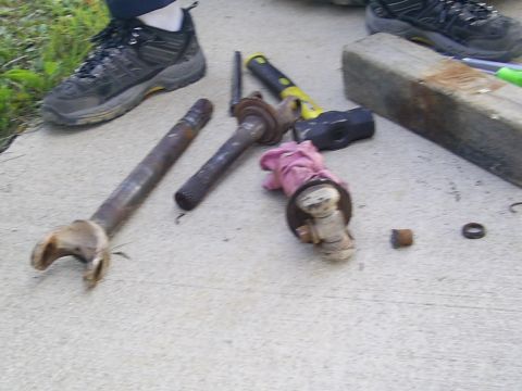 1977 Ford F-150 - Various driveshaft components and tools, including hammers and a pink cloth, are laid out on a concrete surface.