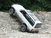 1977 Ford F-150 - A white off-road SUV navigates a challenging rocky terrain, demonstrating its climbing capabilities.