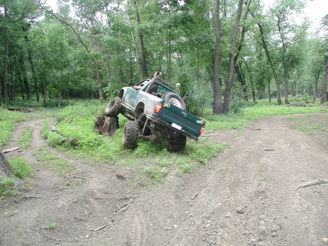 1977 Ford F-150 - Pickup truck navigating a challenging off-road course in a forest setting.