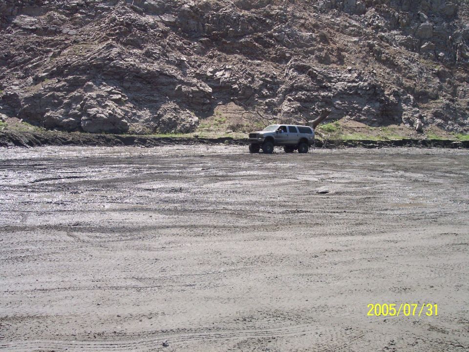 Silver SUV parked on a dirt lot with rocky hillside behind