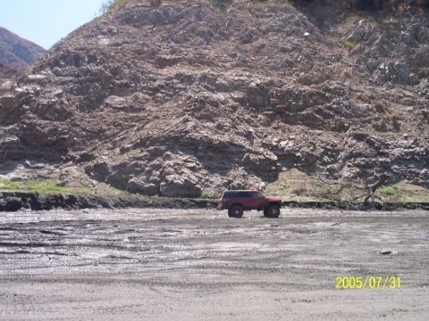 1985 Ford Bronco - Red SUV parked on muddy ground with a rocky hill in the background. Date stamp shows 2005/07/31.