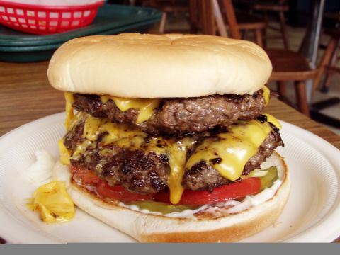 1983 Ford Bronco - A close-up of a double cheeseburger with melted cheese, pickles, tomato, and onion on a bun.