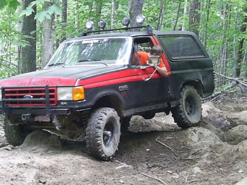 1977 Ford F-150 - This Ford Bronco is navigating a rocky trail in a wooded area.