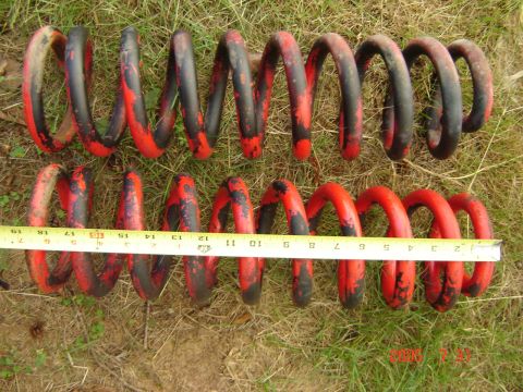 1993 Ford Bronco - A tape measure shows the length of these red and black painted vehicle suspension springs.