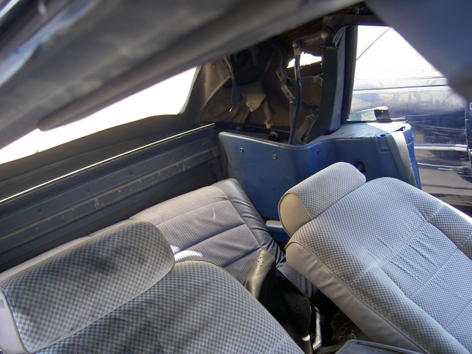 Interior of a blue convertible showing seats and top mechanism