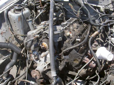 1982 Ford Mustang - The engine bay of a vehicle is shown, with many parts and wires visible.