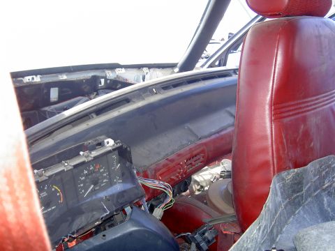 1982 Ford Mustang - The interior of a 1982 Ford Mustang shows red seats and a partially dismantled dashboard with exposed wires.