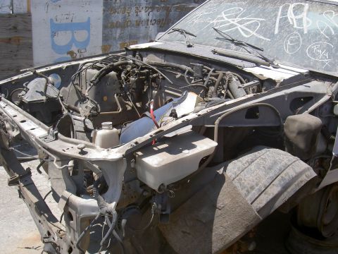 1982 Ford Mustang - Engine bay of a damaged car, with the front fender and tire visible.