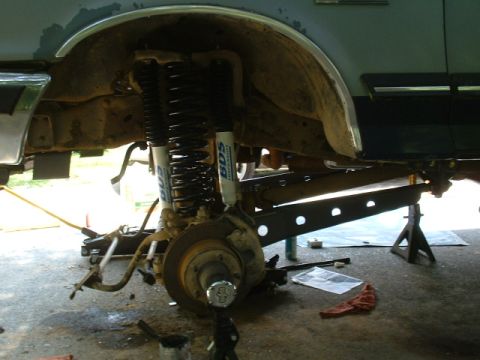 1991 Ford Bronco - The front suspension of a 1991 Ford Bronco is visible, undergoing work with dual shocks and springs.