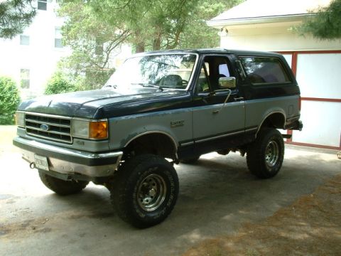 1991 Ford Bronco - This lifted Ford Bronco is parked in a driveway with a garage in the background.