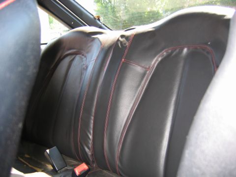 1993 Ford Probe - Rear seats of a car with black leather upholstery and red stitching detail.