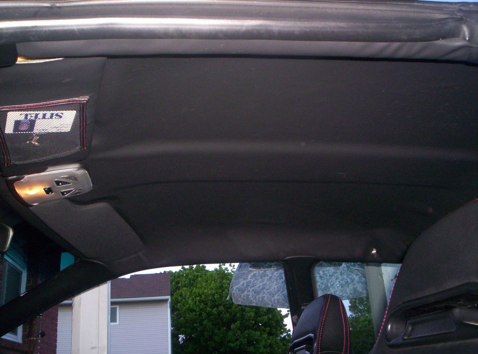 Black headliner and dome light inside a coupe, viewed from the rear seat
