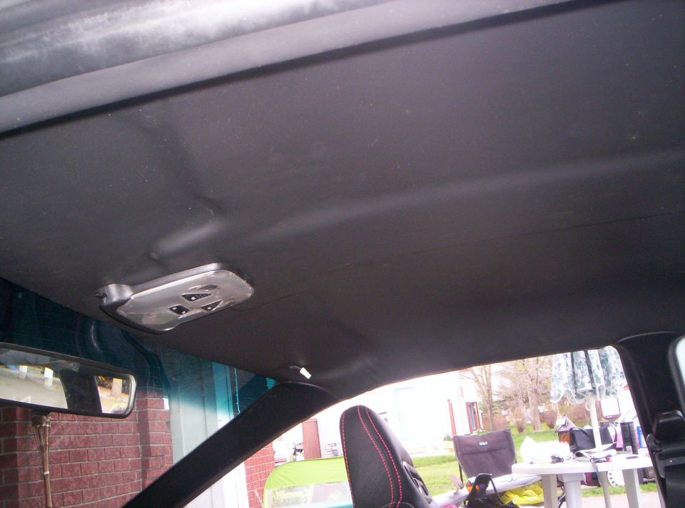 Car interior ceiling with overhead console and rearview mirror visible