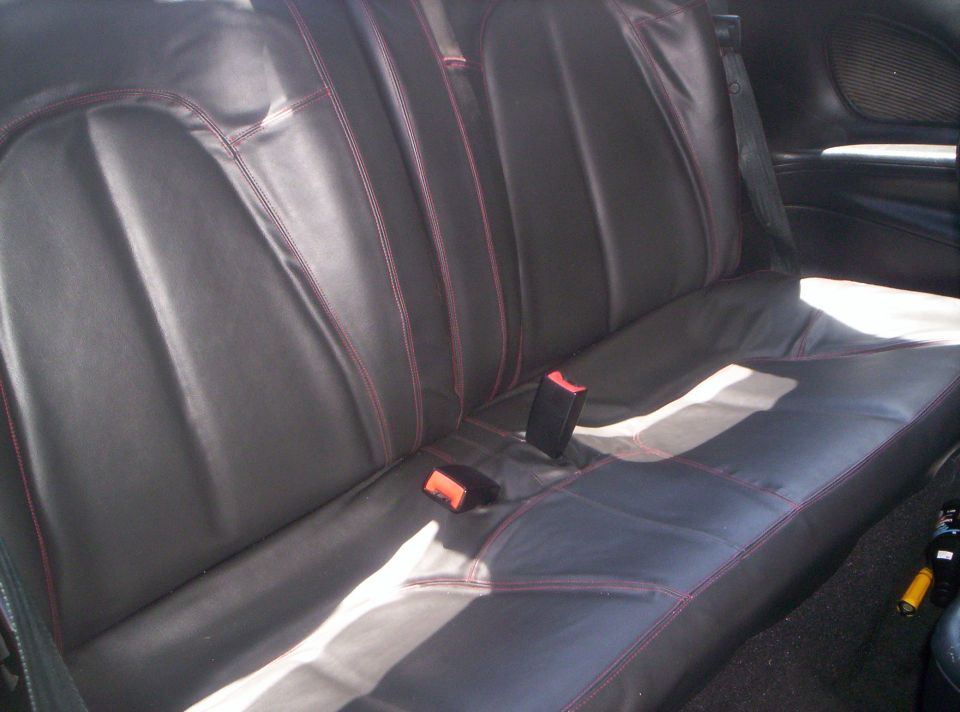 Black rear bench seat with red contrast stitching in a coupe interior