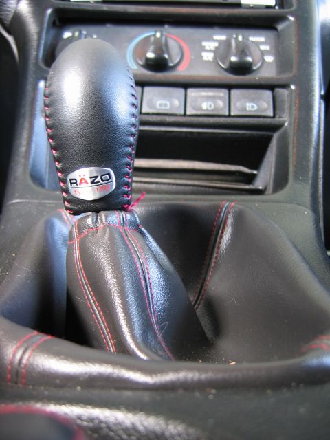 1993 Ford Probe - Close-up of a car's interior gear shift knob and center console, a RAZO branded knob with red stitching.