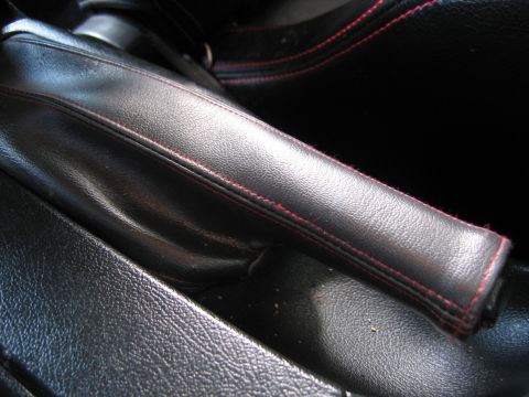 1993 Ford Probe - The interior of a car shows a black leather handbrake with red stitching detail.