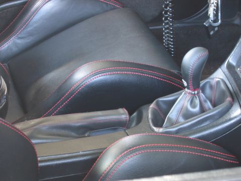 1993 Ford Probe - The interior features black leather seats with contrasting red stitching, visible around the gear shifter and center console.