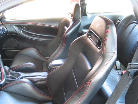 1993 Ford Probe - The interior of a car features black leather racing seats with red contrast stitching and a manual shifter.