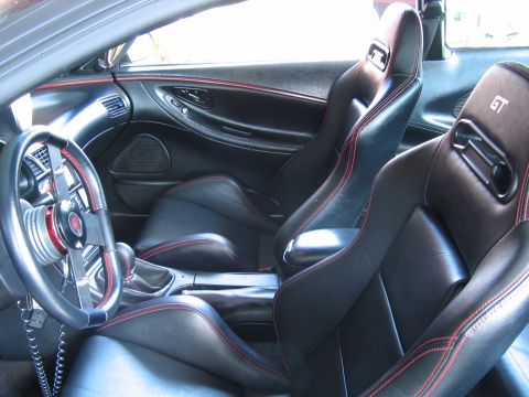 1993 Ford Probe - The interior of a car shows black leather seats with red stitching and GT badging on the headrests.