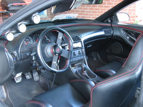 1993 Ford Probe - The interior of a car features aftermarket gauges and seats with red stitching.