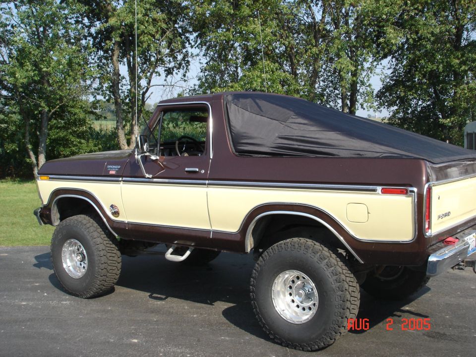 Two-tone brown and tan Ford Bronco, lifted on alloys, soft top, parked on driveway
