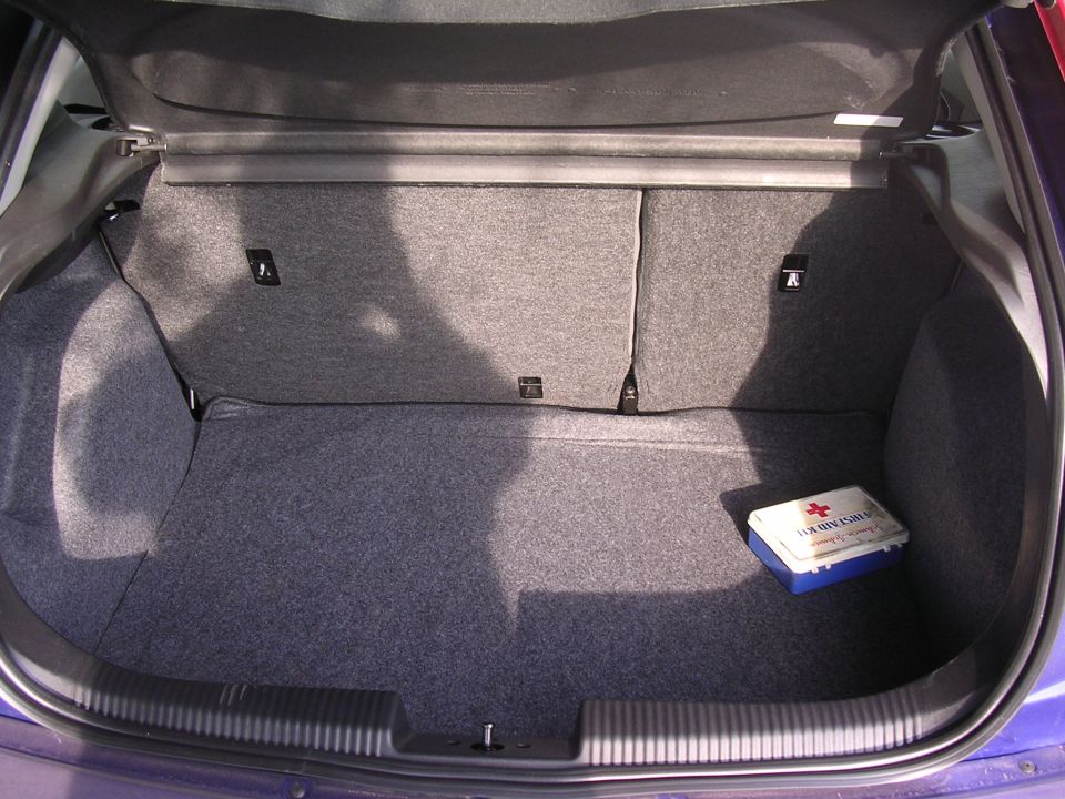 Car trunk interior showing grey carpet and a blue and white first aid kit