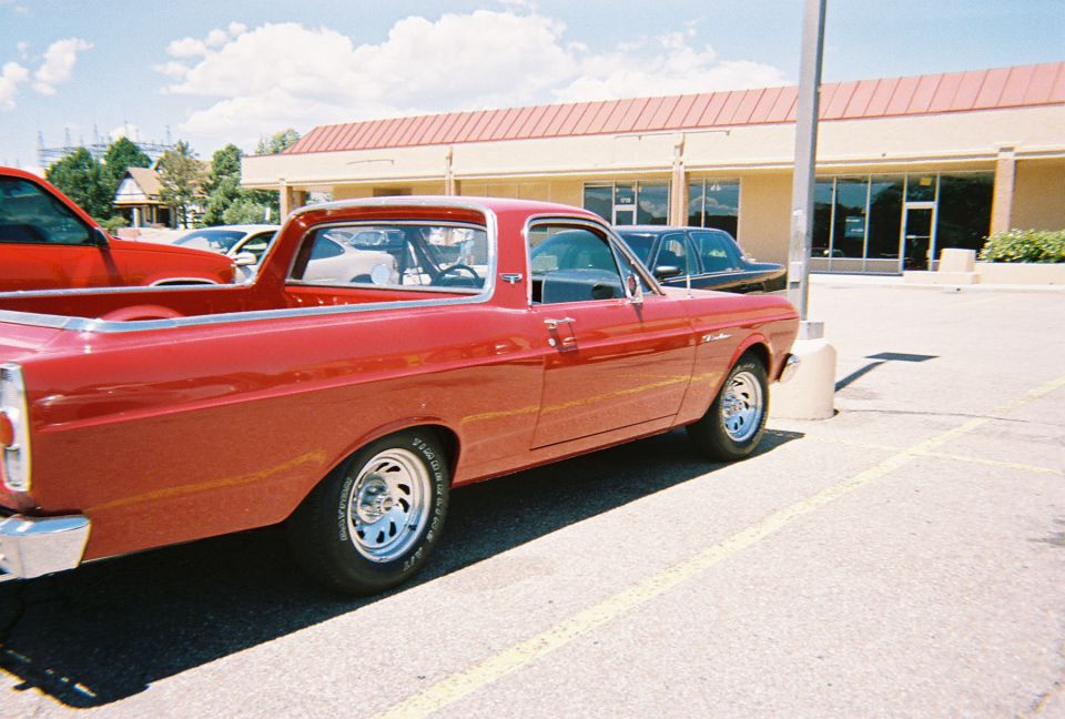 Metallic red Ford Ranchero car-pickup on mag wheels in a parking lot