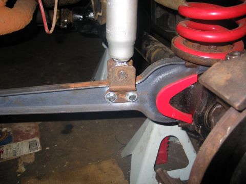 1995 Ford Bronco - Close-up of a vehicle's suspension system being worked on, showing a shock absorber and coil spring.