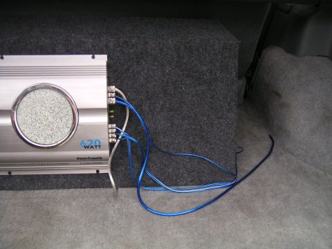 1994 Ford Bronco - A car amplifier labeled "620 WATT" is connected to a subwoofer box inside a vehicle's cargo area.