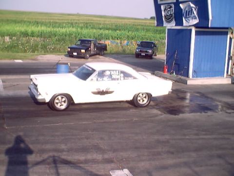 1967 Ford Fairlane - A white coupe sits on a drag strip with a blue building and cornfield in the background.