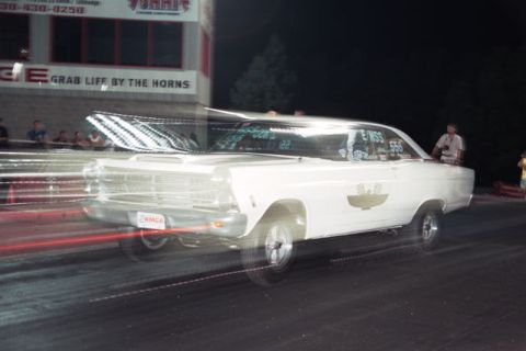 1967 Ford Fairlane - White 1967 Ford Fairlane racing down the drag strip with motion blur. NMCA plate is visible.