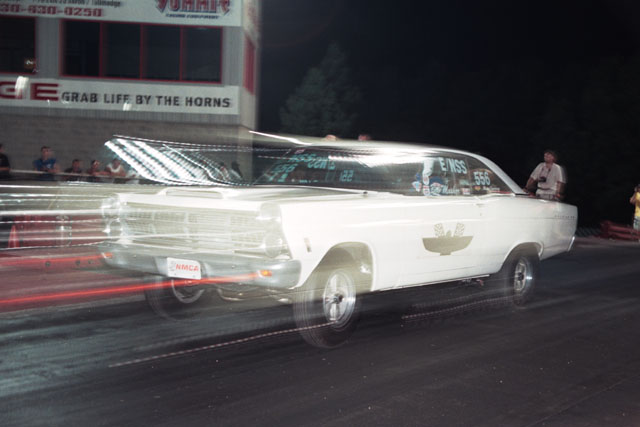 1967 Ford Fairlane drag racing, motion blur on track. NMCA license plate visible