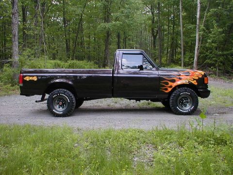1991 Ford F-150 - A 1991 Ford F-150 pickup truck is shown in profile, flame graphics on the front fender and a 4x4 decal on the bed.