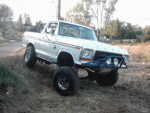 1978 Ford Bronco - This lifted 1978 Ford Bronco navigates a dirt incline, its off-road capabilities with a custom bumper and prominent suspension.