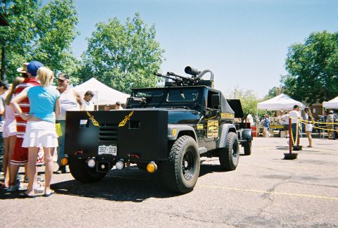 1972 Ford Ranchero - A heavily modified black jeep, resembling a military vehicle with mounted guns and armor, is displayed outdoors.