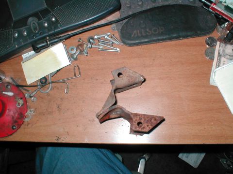 1979 Ford Bronco - A collection of assorted hardware and a rusted metal bracket are laid out on a wooden desk.