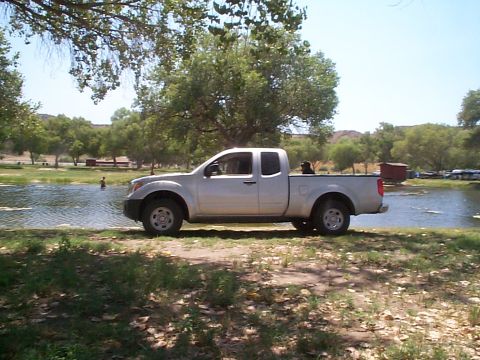 2005 Nissan Frontier - Silver 2005 Nissan Frontier pickup truck parked on grassy bank next to a lake.