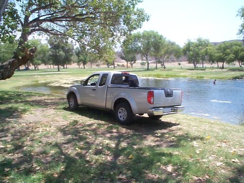 2005 Nissan Frontier - A silver Nissan Frontier pickup truck is parked near the edge of a body of water on a sunny day.